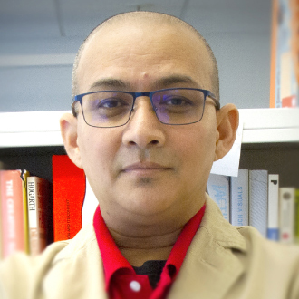 Binod Shrestha, facing forward, bald, black wire-framed glasses, red shirt, yellow jacket
